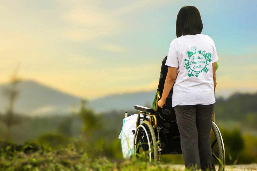 Donna che accompagna invalido su sedia a rotelle