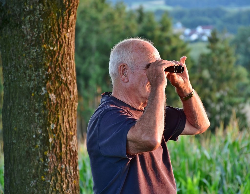 Pensionato con binocolo in mano