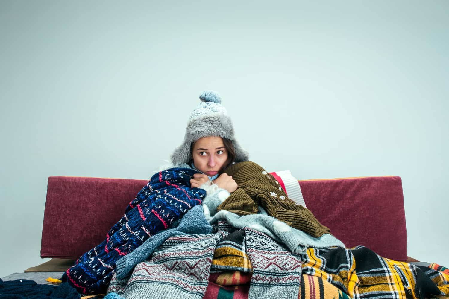 Ragazza coperta di vestiti in casa per ripararsi dal freddo