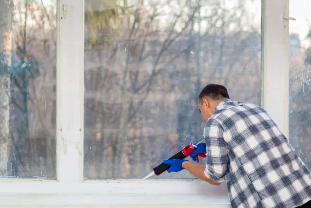 Uomo che mette il silicone sui vetri delle finestre