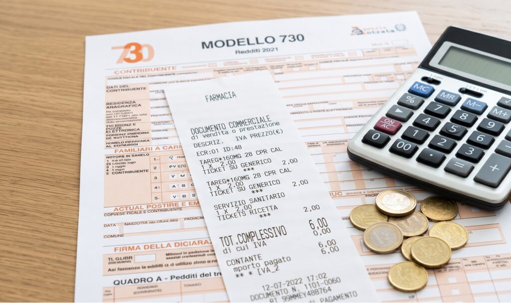 un primo piano nitido di uno scontrino della farmacia appoggiato su un modello 730, con una calcolatrice e delle monete di fianco